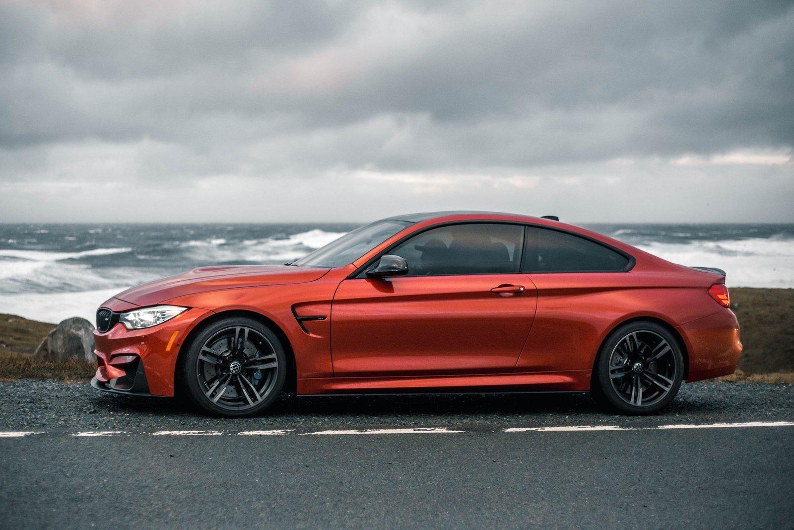 Red sports coupe seen from the side parked by a stormy ocean coast, an illustrative photo for the new cars in the Forza Horizon 6 Series 6 update