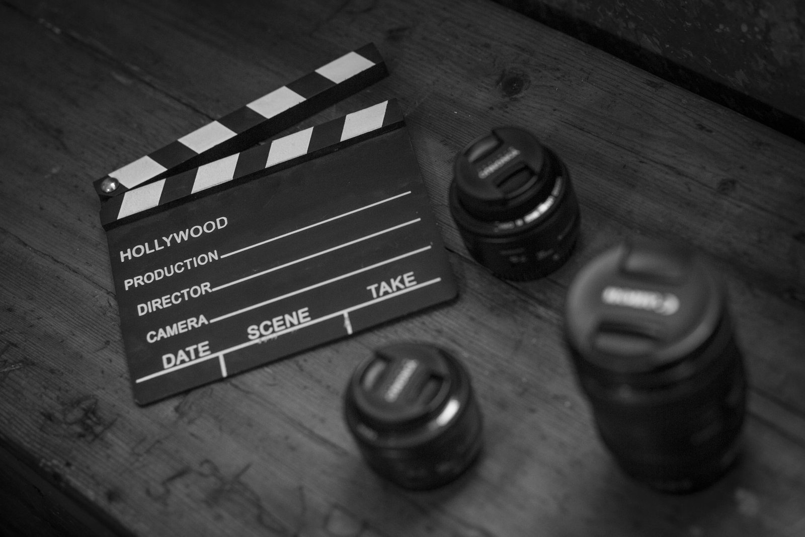 Black and white clapperboard with camera lenses on a wooden table