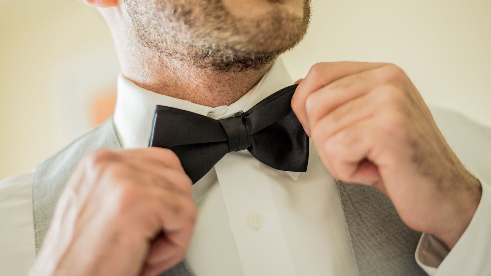 A man adjusting a black bow tie on a white dress shirt, an illustrative real photo for the James Bond casting story